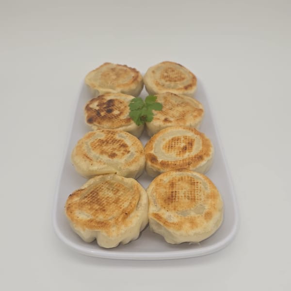 Eight pan-fried Nepalese flatbreads, also known as "aloo paratha," garnished with a sprig of cilantro.