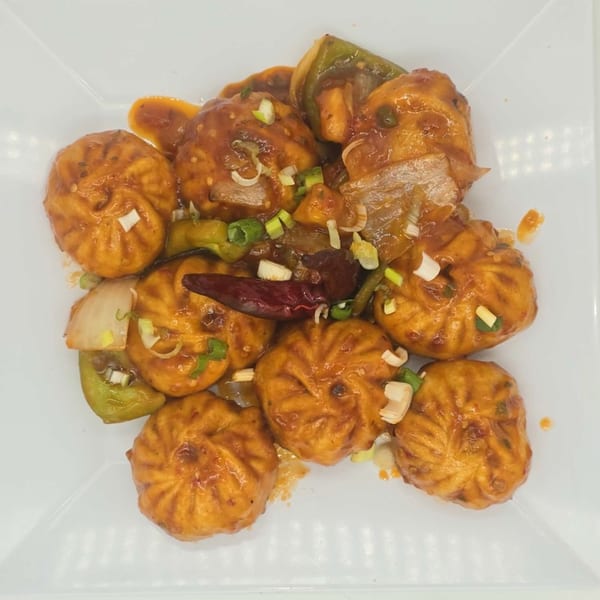 Himalaya on Heights' chili momos, a Nepalese dish, with sauce, peppers, onions, and dried chili.