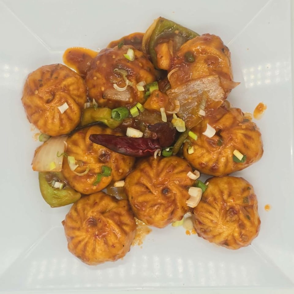 Himalaya on Heights' chili momos, a Nepalese dish, with sauce, peppers, onions, and dried chili.