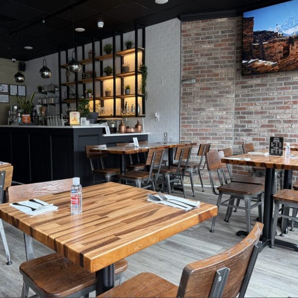 Interior of Himalaya on Heights restaurant with wooden tables, industrial chairs, and a brick wall.