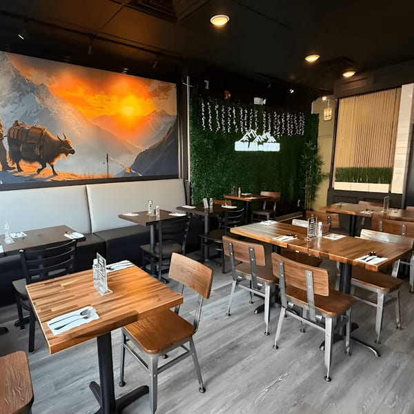 Interior of Himalaya on Heights restaurant with tables, chairs, and a large mural of mountains and a yak.